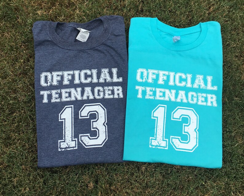 May include: Two t-shirts, one blue and one turquoise, with the text "OFFICIAL TEENAGER 13" printed on them.