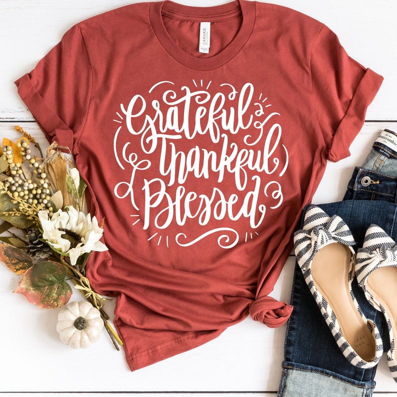 May include: A rust-colored t-shirt with the text "Grateful & Thankful Blessed" in white lettering.