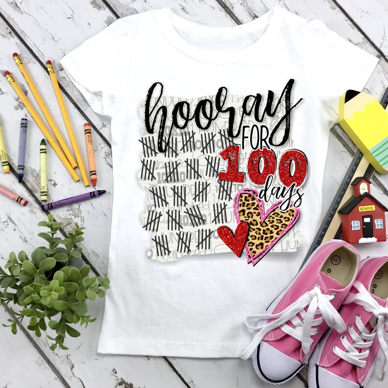 Peut inclure: T-shirt blanc avec un graphique noir et blanc qui dit "hooray for 100 days". Le graphique comprend un c&oelig;ur rouge avec des paillettes et un c&oelig;ur imprim&eacute; l&eacute;opard.