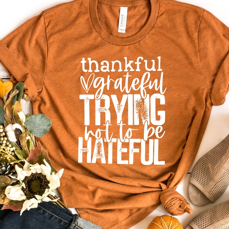 Puede incluir: Una camiseta marr&oacute;n con texto blanco que dice "thankful grateful trying not to be hateful".
