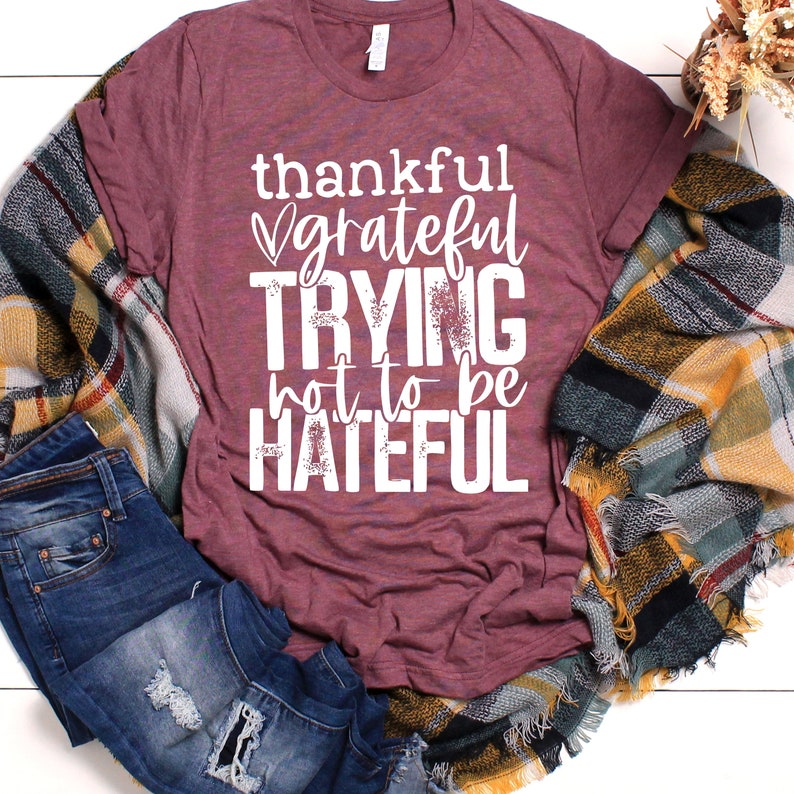 Puede incluir: Una camiseta color burdeos con un gr&aacute;fico blanco que dice "thankful grateful trying not to be hateful".