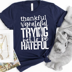 Puede incluir: Camiseta azul marino con texto blanco que dice "thankful grateful trying not to be hateful".