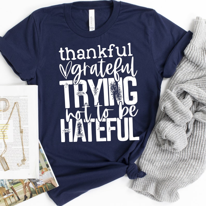 Puede incluir: Camiseta azul marino con texto blanco que dice "thankful grateful trying not to be hateful".