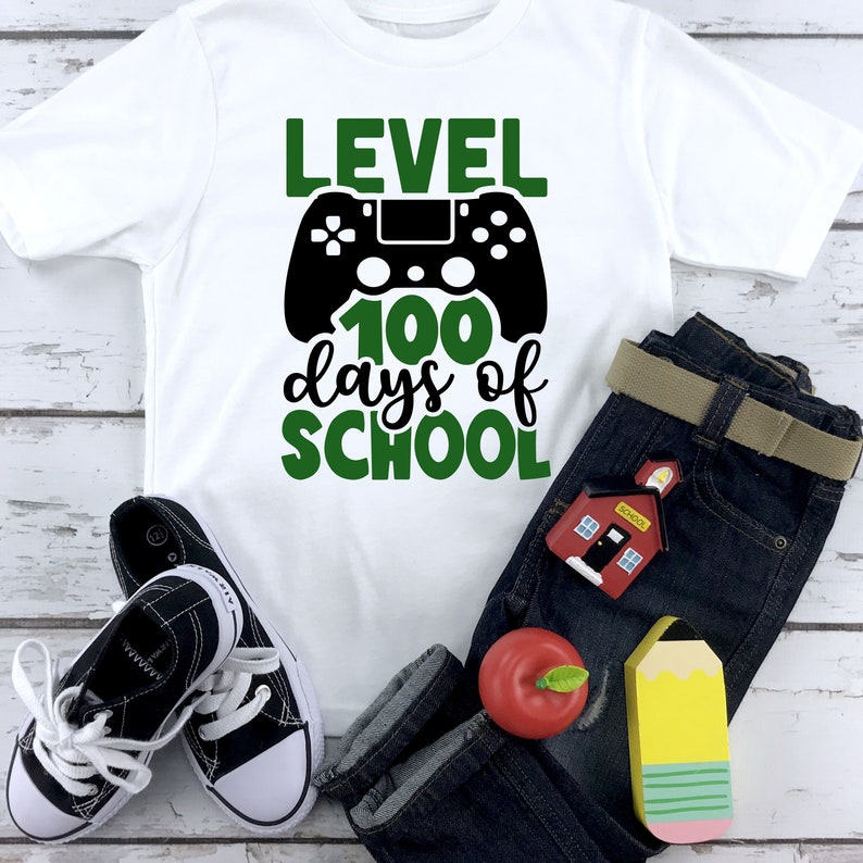 May include: White t-shirt with a green and black graphic that says "Level 100 days of school" with a video game controller design.