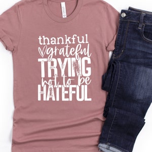 Puede incluir: Una camiseta color malva con el texto "thankful grateful trying not to be hateful" impreso en blanco.