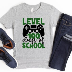 May include: Gray t-shirt with a green and black graphic of a video game controller and the text "Level 100 days of school".
