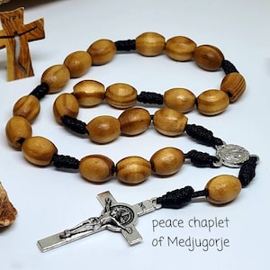May include: A wooden olive wood rosary with black cord and silver crucifix and medal. The rosary is called a "peace chaplet of Medjugorje".