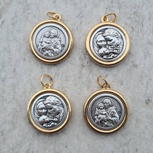 May include: Four silver and gold pendants with religious imagery. Each pendant features a different image of a family with a child. The pendants are round and have a gold rim.