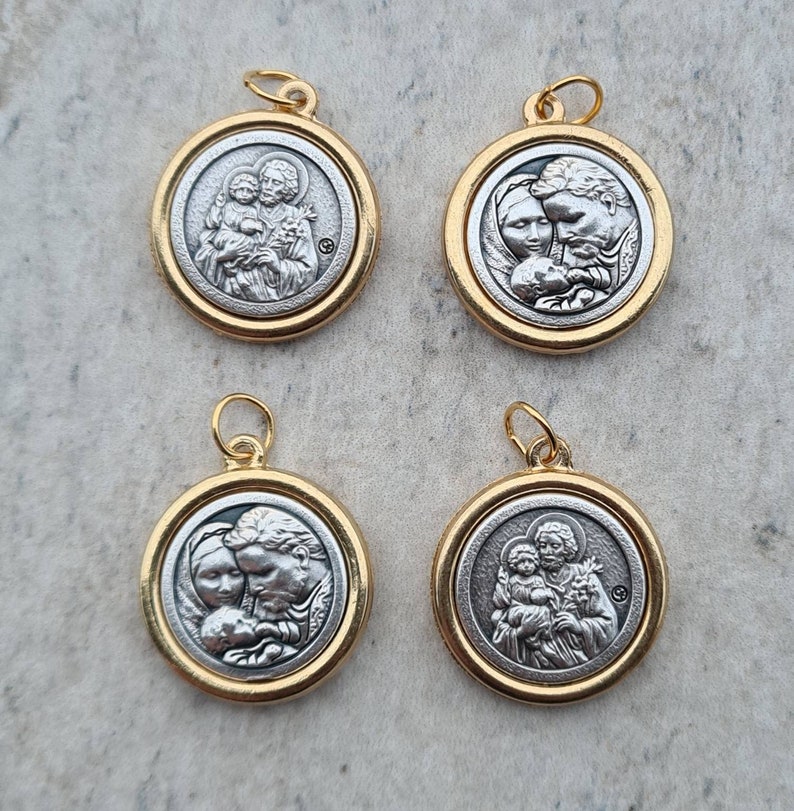 May include: Four silver and gold pendants with religious imagery. Each pendant features a different image of a family with a child. The pendants are round and have a gold rim.
