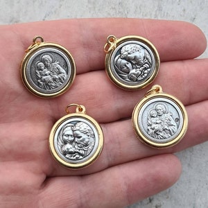 May include: Four gold-toned pendants featuring silver-toned images of Saint Joseph, Mary, and baby Jesus. The pendants are round and have a smooth, shiny finish.