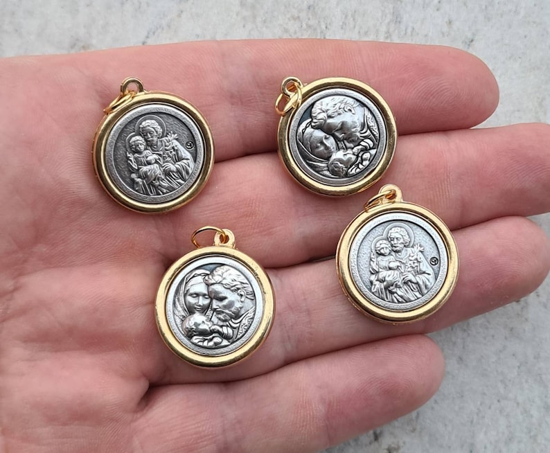 May include: Four gold-toned pendants featuring silver-toned images of Saint Joseph, Mary, and baby Jesus. The pendants are round and have a smooth, shiny finish.