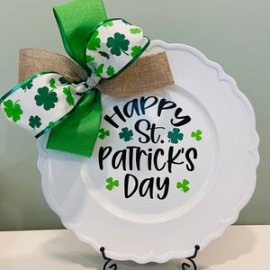 May include: White decorative plate with a green and white bow and the text "Happy St. Patrick's Day" in black lettering with green shamrocks.