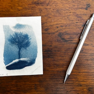 May include: A blue and white watercolour painting of a bare tree on a hill. The painting is signed "cr 11" in the bottom left corner.