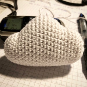 May include: A white crocheted cloud-shaped amigurumi toy. The toy is made with a single crochet stitch and has a smooth, rounded shape.