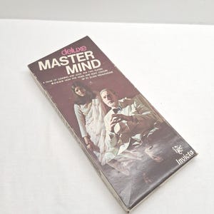 May include: A vintage "Deluxe Master Mind" board game box. The box is brown with the game title in large white letters and the Invicta logo. The box features an image of two people and text that reads "A game of cunning and logic for two players."
