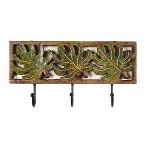 Puede incluir: Un colgador de llaves de pared de madera con tres ganchos. La madera está tallada con un diseño de tres hojas verdes.