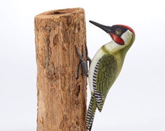 Single painted green woodpecker carving on a driftwood log.