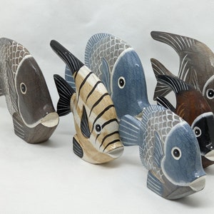 May include: Five wooden fish figurines in various colours and patterns. The fish are arranged in a row, with the largest fish on the left and the smallest fish on the right. The fish are painted in shades of brown, blue, grey, and yellow.