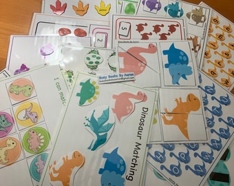 Puede incluir: Un conjunto de hojas de actividades educativas imprimibles con temática de dinosaurios para niños. Las hojas presentan ilustraciones coloridas de dinosaurios, números, letras y actividades de emparejamiento. Las hojas están tituladas "Busy Books by Aaron" e incluyen la dirección de correo electrónico "busybooksbyaaron@gmail.com".