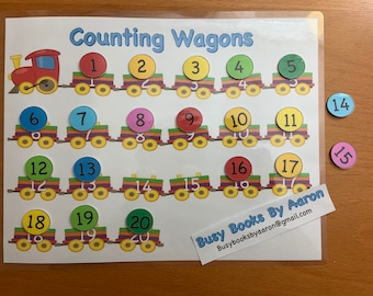 May include: A colorful counting train with 20 wagons, each with a different number on it. The numbers are on colorful circles and the wagons are on a white background. The train is on a white background with the words "Counting Wagons" at the top. There are also two loose circles with the numbers 14 and 15 on them.