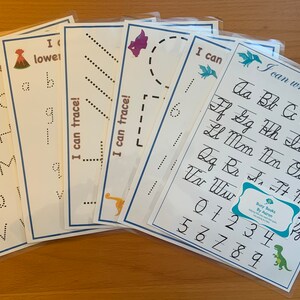 Può includere: Un set di sei fogli di lavoro stampabili per bambini per esercitarsi a tracciare lettere e numeri. I fogli di lavoro presentano un tema di dinosauri e includono lettere maiuscole, lettere minuscole, lettere corsive e numeri. I fogli di lavoro sono stampati su carta bianca e hanno un bordo blu.