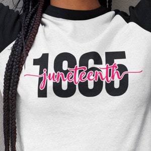 May include: A white t-shirt with black raglan sleeves and a black and pink graphic that says "1865 juneteenth".