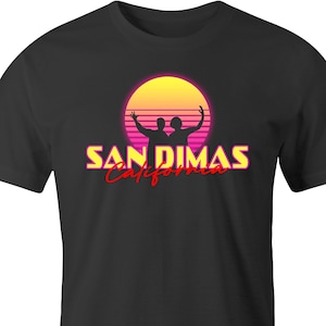 May include: Black t-shirt featuring a retro design with a yellow and pink sunset, two silhouetted figures, and the text "SAN DIMAS California" in yellow and red. The shirt is a classic crew neck.