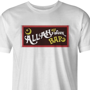 Puede incluir: Camiseta blanca con un gráfico rectangular rojo y negro que dice "ALLAH NU WUNK BAR" en letras amarillas con una luna creciente y una estrella sobre el texto.