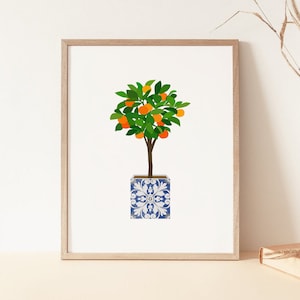 Op de afbeelding: Een ingelijste print van een gestileerde illustratie van een kleine sinaasappelboom met groene bladeren en sinaasappelen in een blauw-wit gepatroneerde pot.