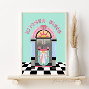Peut inclure: Une impression encadrée turquoise et blanche avec le texte "Kitchen Disco" en lettres roses. L'impression présente un juke-box de style rétro avec un schéma de couleurs rose, bleu et gris.