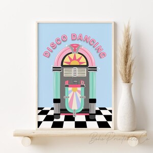 Peut inclure: Une illustration rétro d'un juke-box avec le texte "Disco Dancing" en lettres roses avec des accents de paillettes. Le juke-box est sur un sol à carreaux noirs et blancs sur un fond bleu clair.