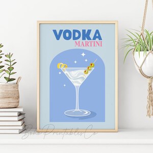 May include: A blue and white illustration of a vodka martini with a lemon twist and olives. The text "VODKA MARTINI" is in blue and pink letters.