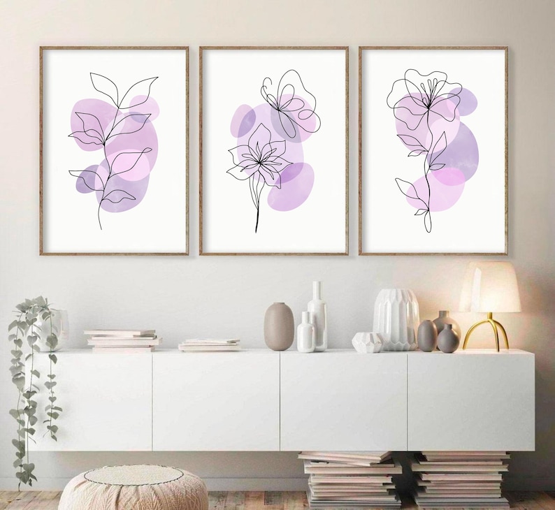 May include: Three framed prints featuring minimalist line drawings of flowers and a butterfly on a white background. The flowers are outlined in black and have purple watercolour washes behind them.