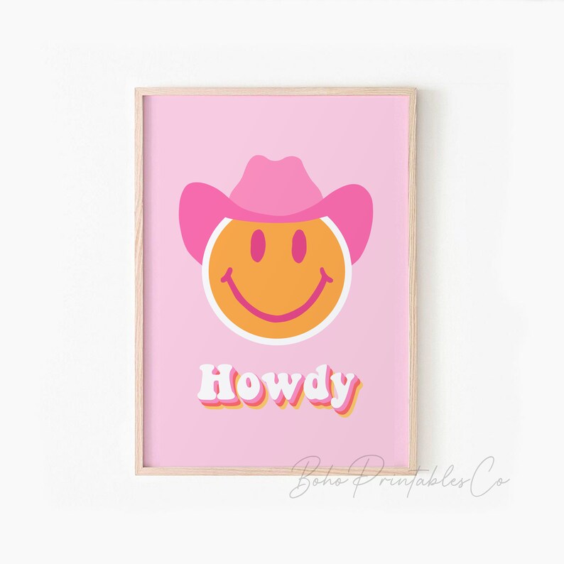 May include: Pink and orange smiley face wearing a pink cowboy hat with the word "Howdy" in retro font on a pink background.