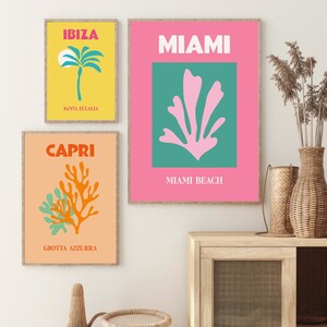 May include: Three colorful travel posters with illustrations of a palm tree, a coral reef, and a sea plant. The posters are framed in wood and have the text "IBIZA SANTA EULALIA", "MIAMI MIAMI BEACH", and "CAPRI GROTTA AZZURRA".