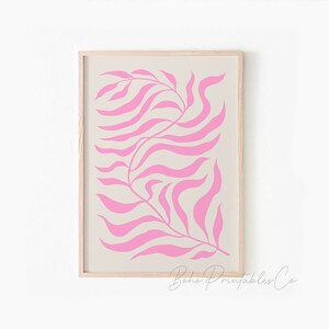 May include: A digital print of a pink stylized leaf design on a beige background. The print is framed in a light wood frame.