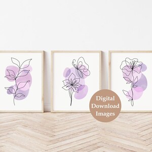 May include: Set of three digital prints featuring abstract line art floral designs with purple watercolour accents. The prints are framed and displayed on a white wall.