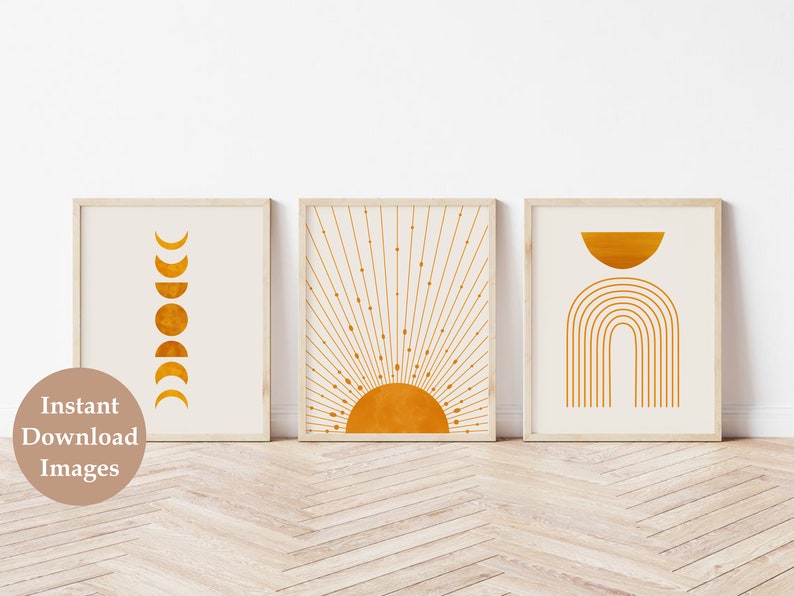 May include: Three minimalist wall art prints with a white background and gold geometric shapes. The first print features a series of crescent moons, the second print features a sun with rays, and the third print features a half circle and an arch.
