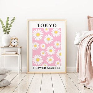 May include: A framed print with a pink background and white daisies. The print says "TOKYO FLOWER MARKET" at the bottom.