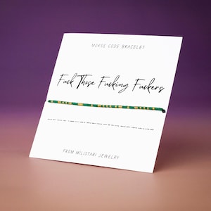 May include: A Morse code bracelet with green and gold beads is displayed on a white card. The card has the text "Fuck Those Fucking Fuckers" in cursive. The card also includes the text "MORSE CODE BRACELET" and "FROM MILISTARI JEWELRY".