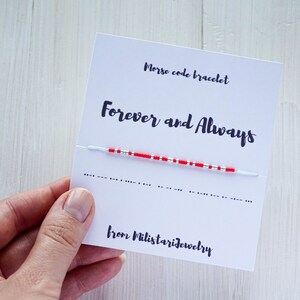 Peut inclure: Une carte blanche avec des perles rouges et argentées enfilées sur une ficelle blanche. La carte indique "Bracelet code morse" et "Forever and Always" en texte noir. La carte indique également "from Milistariejewelry" en texte noir.