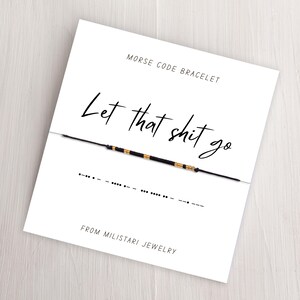 May include: A white card with black text that reads "Morse Code Bracelet" and "Let that shit go". The card also includes a black string bracelet with gold beads and the Morse code for the phrase.