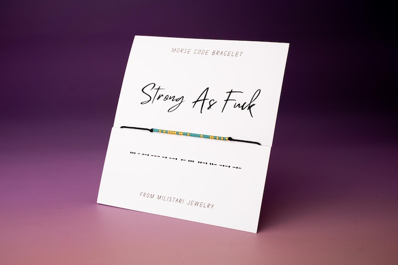 Morse code bracelet spelling “Strong As Fuck” with bold message hidden in minimalist beaded design.