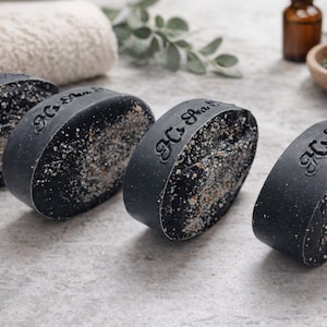 May include: A white ceramic mug with a black handle and the text "But First, Coffee" in a bold, black font. The mug is set against a neutral background, highlighting its simple design.