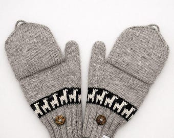 May include: A pair of grey knit convertible mittens featuring a fold-over cap design. The mittens display a horizontal band with a repeating black and white llama pattern, a single brown button on each wrist, and a small white brand tag.