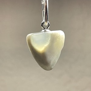 May include: A silver chain necklace with a white and grey iridescent stone pendant. The stone is shaped like a triangle and has a smooth, polished surface.