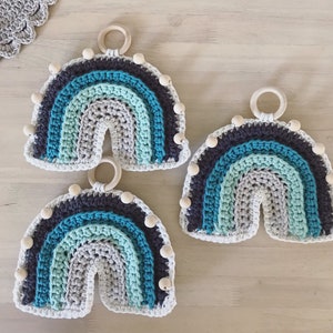 May include: Three crocheted rainbow wall hangings with wooden beads. Each rainbow is made with different shades of blue and gray yarn.