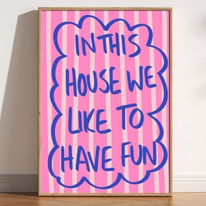 May include: A pink and white striped poster with a blue cloud shape containing the text "In this house we like to have fun".