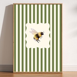 May include: A framed print with a green and white striped background. A white oval with a rounded edge contains a watercolour illustration of a bumblebee.