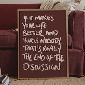 Könnte beinhalten: Ein rechteckiges gerahmtes Wandbild mit dunkelmarunfarbenem Hintergrund und weißem, handgeschriebenem Text: If it makes your life better and hurts nobody, that's really the end of the discussion. Der Rahmen besteht aus hellem Holz.